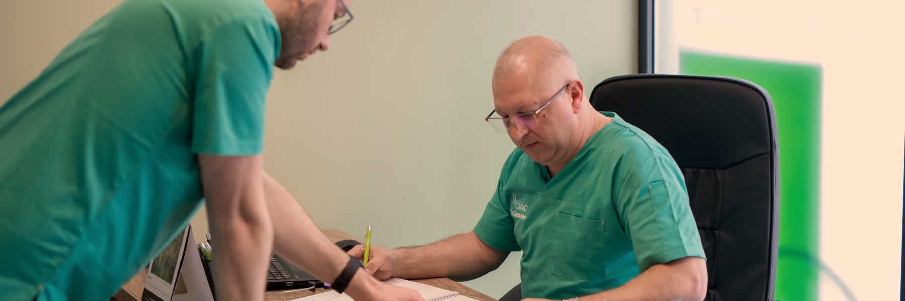 Doi medici A Clinic la birou, aplecați peste documentele unui pacient