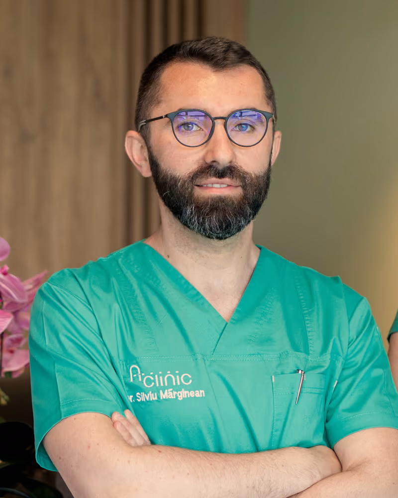 Dr. Silviu Mărginean, medic specialist chirurgie generală, în halat verde A Clinic, la recepția clinicii